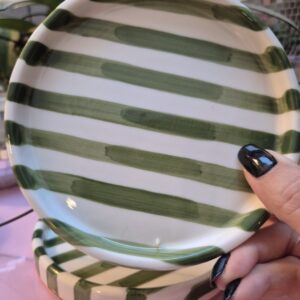 A close-up photo of a handmade small ceramic plate with a smooth gloss glaze in soft off-white and Green stripes.