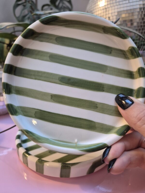 A close-up photo of a handmade small ceramic plate with a smooth gloss glaze in soft off-white and Green stripes.