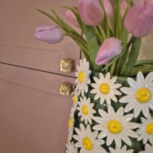 A close-up photo of a handmade ceramic Green vase with a smooth, gloss glaze in soft Green. The natural light casting gentle shadows that highlight its colourway of Red love hearts or Pink love hearts.